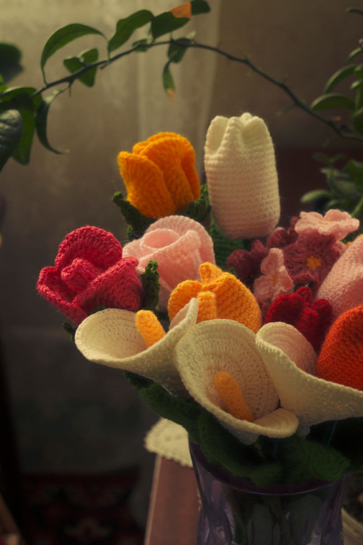 A handmade crochet flower bouquet arranged in a glass vase